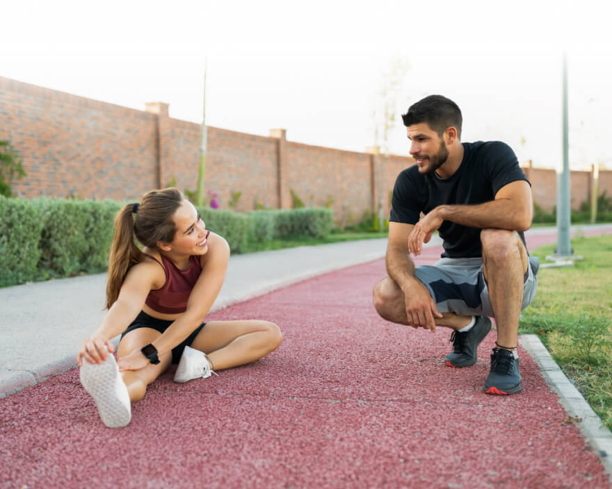 Two runners stretching and resting beside a running track