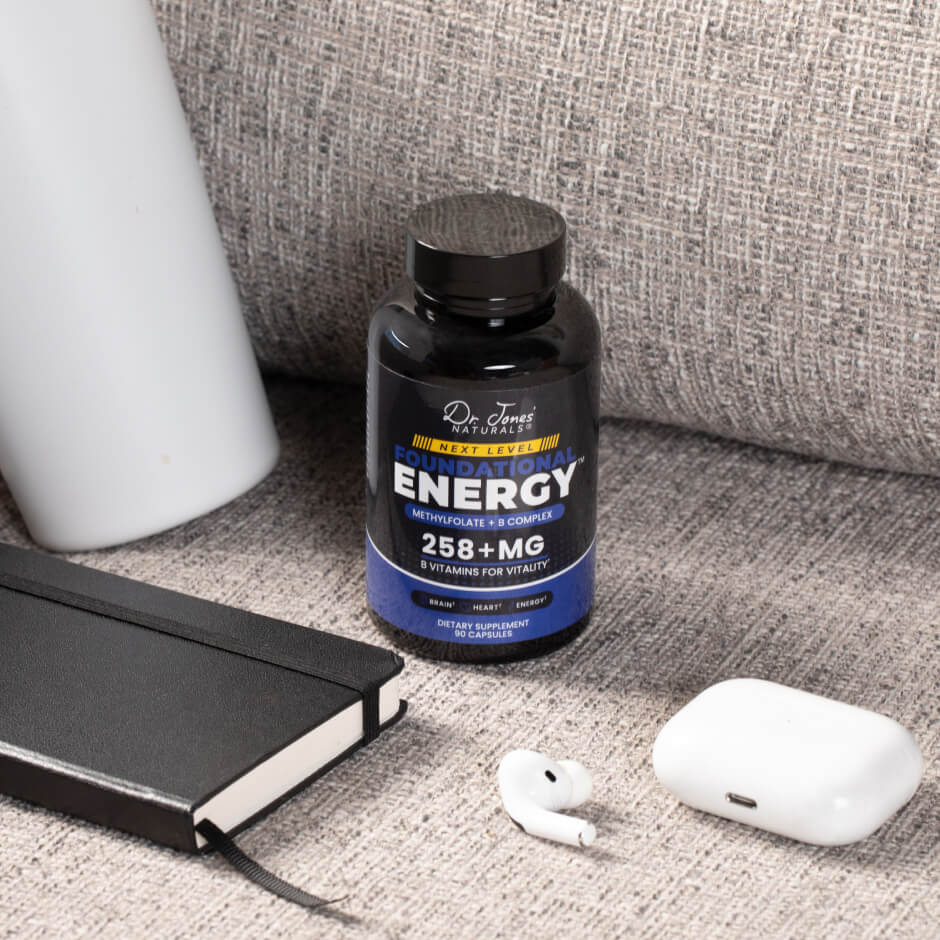 A bottle of Dr. Jones&rsquo; Naturals Energy 258+MG on a sofa beside a notebook and earbuds